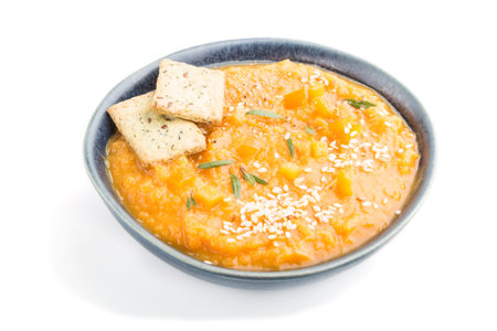 Sweet potato or batata cream soup with sesame seeds and snacks in blue ceramic bowls isolated on...
