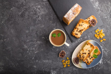 Homemade cake with raisins, dried persimmon and a cup of hot chocolate on a black concrete...