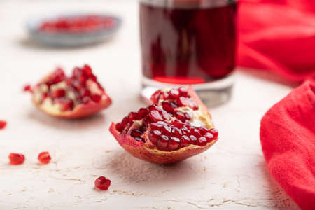 Glass of pomegranate juice on a white concrete background with red textile. Side view, close up, selective focus.の写真素材
