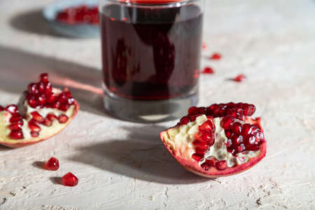 Glass of pomegranate juice on a white concrete background. Hard light, contrast. Side view, close up, selective focus.の写真素材
