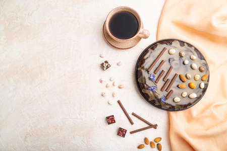Homemade chocolate brownie cake with caramel cream and almonds with cup of coffee on a white concrete background and orange textile. top view. flat lay, copy space.の写真素材