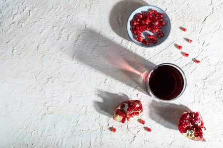 Glass of pomegranate juice on a white concrete background. Hard light, contrast. Top view, copy...