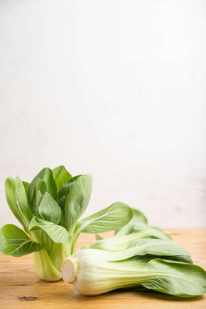 Fresh green bok choy or pac choi chinese cabbage on a brown wooden background. Side view, copy space, selective focus.の写真素材
