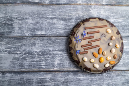 Homemade chocolate brownie cake with caramel cream and almonds on a gray wooden background. top...