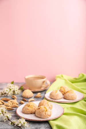 Almond cookies and a cup of coffee on a gray and pink background and green linen textile. Side view, close up, selective focus, copy space.の写真素材