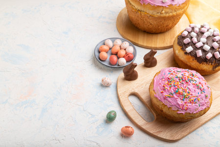 Homemade glazed and decorated easter pies with chocolate eggs and rabbits on a white concrete...
