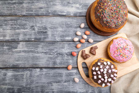 Homemade glazed and decorated easter pies with chocolate eggs and rabbits on a gray wooden background and linen textile. top view, flat lay, copy space.の写真素材