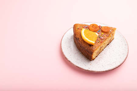 A piece of orange cake on a pastel pink background. Side view, copy space, close up.の写真素材