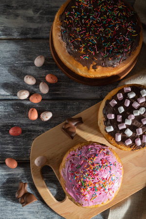 Homemade glazed and decorated easter pies with chocolate eggs and rabbits on a gray wooden...