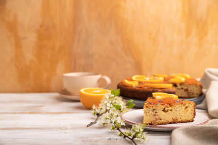 Orange cake and a cup of coffee on a white wooden background and linen textile. Side view, copy space, selective focus.の写真素材