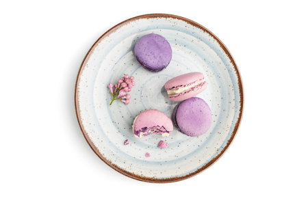 Purple macarons or macaroons cakes on blue plate isolated on white background. Top view, flat lay,...