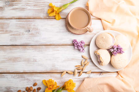 Meringues cakes with cup of coffee on a white wooden background and orange linen textile. Top view, flat lay, copy space.の写真素材