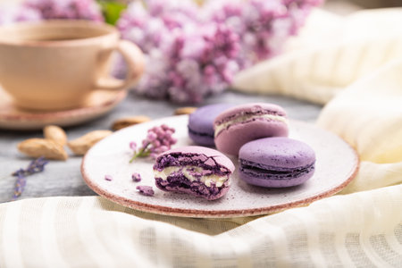 Purple macarons or macaroons cakes with cup of coffee on a gray wooden background and white linen...