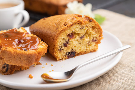 Homemade cake with raisins, almonds, soft caramel and a cup of coffee on a black concrete background...