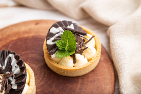 Sweet tartlets with chocolate and cheese cream with cup of coffee on a white wooden background and...