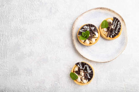 Sweet tartlets with chocolate and cheese cream on a gray concrete background. top view, flat lay, copy space.の写真素材