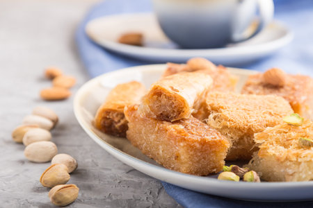 traditional arabic sweets (basbus, kunafa, baklava) and a cup of coffee on a gray concrete...