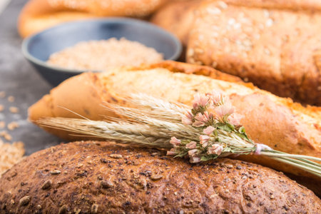 Different kinds of fresh baked bread and blue plate with grains on a black concrete background. side...