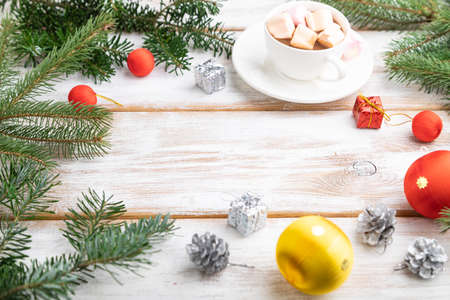 Christmas or New Year frame composition. Decorations, red balls, cones, fir and spruce branches, cup of coffee, on a white wooden background. Side view, copy space.の写真素材