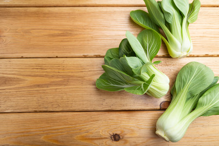Fresh green bok choy or pac choi chinese cabbage on a brown wooden background. Top view, copy space, flat lay.の写真素材