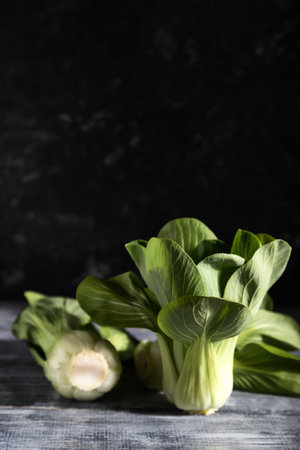 Fresh green bok choy or pac choi chinese cabbage on a gray wooden background. Hard light, contrast, dark, moody. Side view, copy space, selective focus.の写真素材