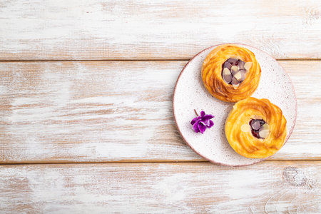 Small cheesecakes with jam and almonds on a white wooden background. top view, flat lay, copy space.