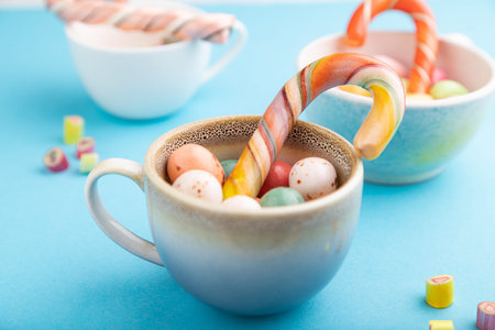 Heap of multicolored caramel candies in cups on blue pastel background. close up, side view,...