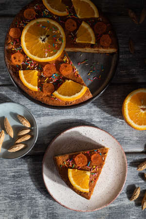 Orange cake on a gray wooden background. Hard light. contrast, low key. Top view, flat lay, close up.の写真素材