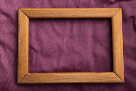 Wooden frame on smooth cotton purple tissue. Top view, flat lay, natural textile background and...