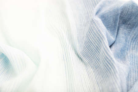 Fragment of blue and white linen tissue. Side view, textile blurred background and texture. Water and wave concept.の写真素材