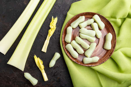 Jelly celery candies on black concrete background and green linen textile. close up, top view, flat lay.の写真素材