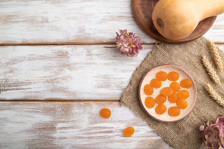 Jelly pumpkin candies on white wooden background and linen textile. copy space, top view, flat lay. autumn concept.