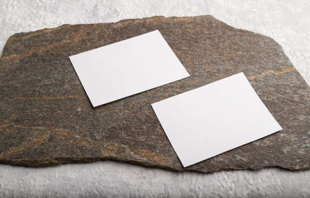 White paper business card, mockup with natural stone on gray concrete background. Blank, side view, still life, copy space.の写真素材