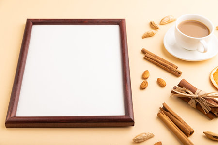 Composition with wooden frame, almonds, cinnamon and cup of coffee. mockup on orange background. Blank, flat lay, top view, still life, copy space.の写真素材
