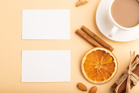 Composition of white paper business cards, almonds, cinnamon and cup of coffee. mockup on orange...