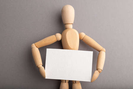 Wooden mannequin holding blank poster on gray pastel background. copy space, isolated, presentation concept.の写真素材