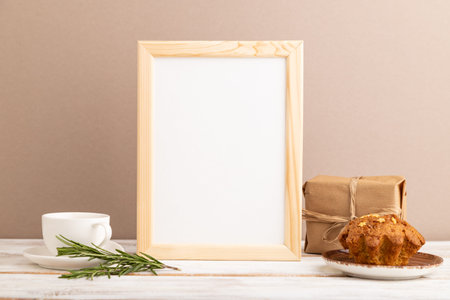 White wooden frame mockup with cup of coffee and cake on brown background. Blank, side view, still life.の写真素材
