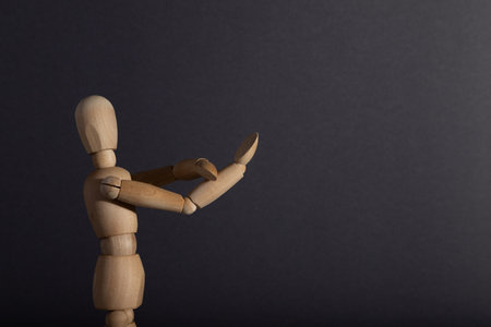 Wooden mannequin shows obscene gesture fuck off with hands on gray background. protest, riot, agression, contempt concept. copy space, hard light.の写真素材