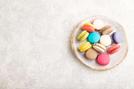 Multicolored macaroons on ceramic plate on gray concrete background. top view, copy space, still life. Breakfast, morning, concept.の写真素材