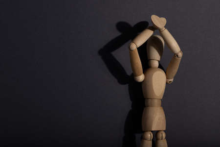 Wooden mannequin stands with raised hands on gray background. protest, attention concept. copy space, hard light.の写真素材