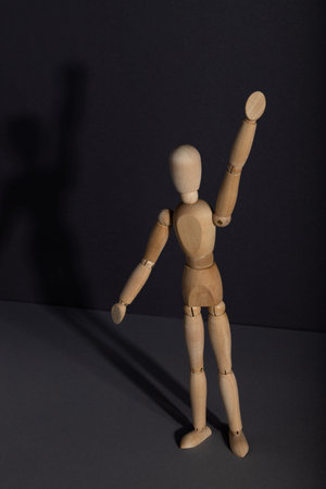 Wooden mannequin stands with raised hand on gray background. protest, attention concept. copy space,...