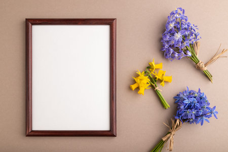 Wooden frame with spring snowdrop flowers bluebells, narcissus on beige pastel background. top view,...