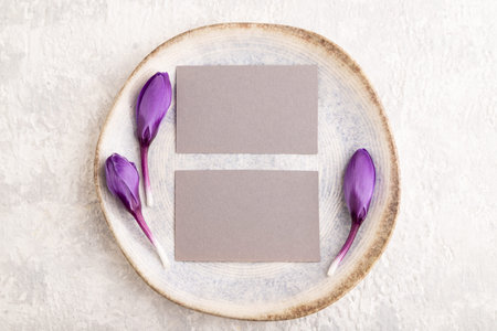 Gray paper invitation card, mockup with crocus flowers on ceramic plate and gray concrete...