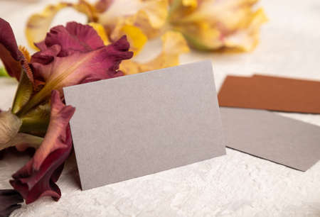 Gray business card with iris flowers on gray concrete background. side view, copy space, still life. Breakfast, morning, spring concept.の写真素材