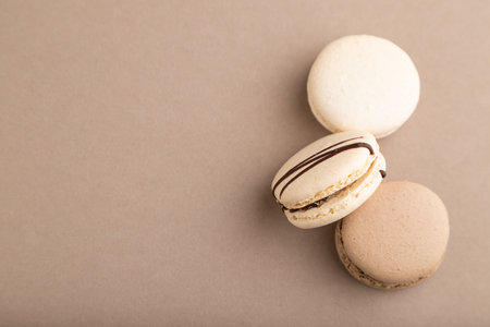 Brown and white macaroons on beige pastel background. top view, flat lay, copy space, still life. Breakfast, morning, concept.の写真素材