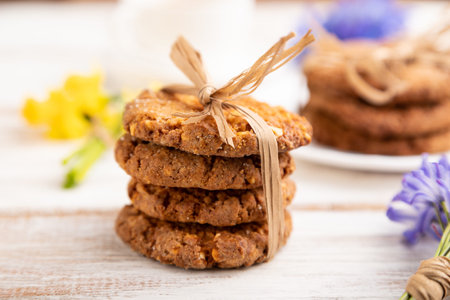Oatmeal cookies with spring snowdrop flowers bluebells, narcissus and cup of coffee on white wooden background. side view, close up, defocused, still life. Breakfast, morning, spring concept.の写真素材