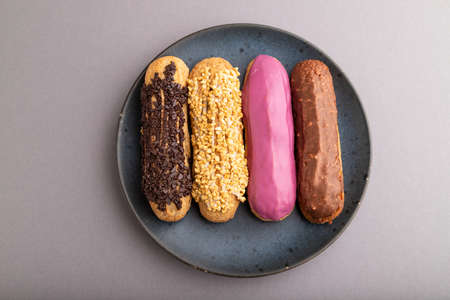 Set of eclair, traditional french dessert on blue ceramic plate on gray pastel background. top view, flat lay, close up, still life. Breakfast, morning, concept.の写真素材