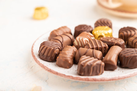 Chocolate candies with cup of coffee and hydrangea flowers on a white concrete background. side...