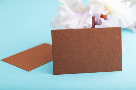 Brown business card with lilac iris flowers on blue pastel background. side view, copy space, still life. Breakfast, morning, spring concept.の写真素材