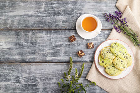 Green cookies with chocolate and mint on ceramic plate with cup of green tea and linen textile on gray wooden background. top view, flat lay, copy space.の写真素材